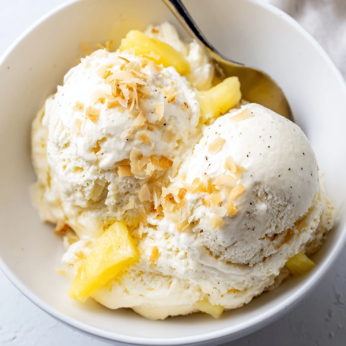 Homemade Creamy Pineapple Ice Cream with tangy pineapple chunks, toasted coconut sprinkle