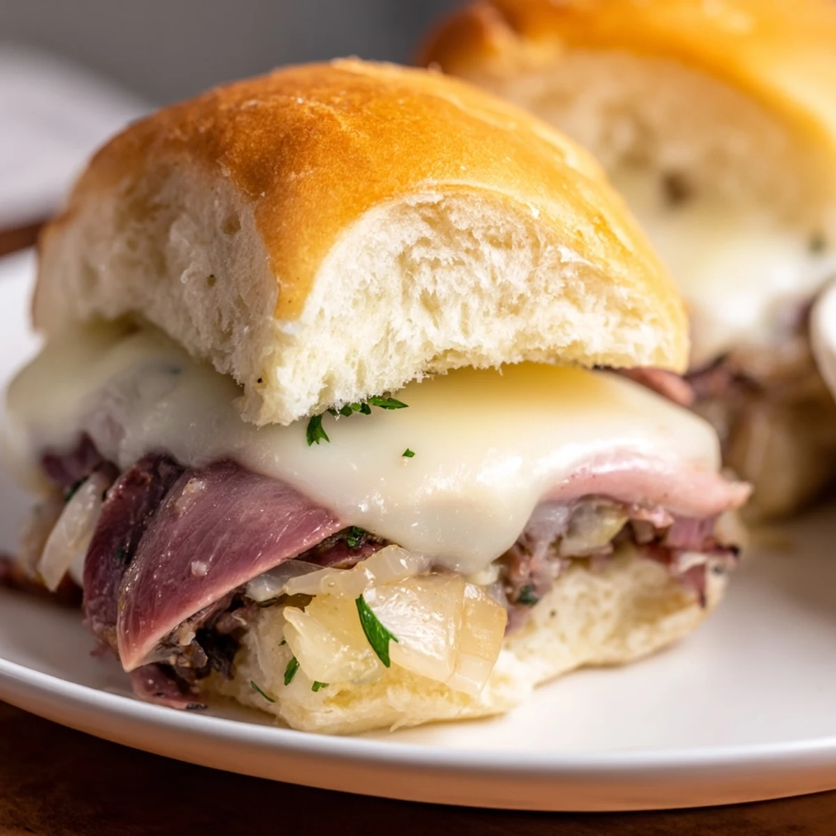 Tender roast beef French dip sliders stacked on toasted brioche rolls with caramelized onions