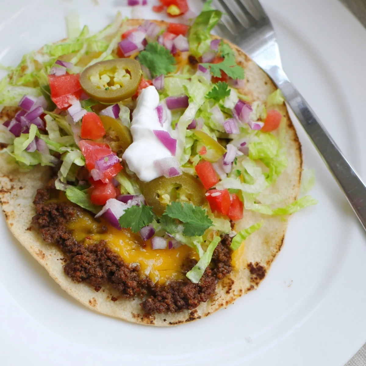 Stack of Blackstone smash tacos featuring crispy beef edges oozing cheese and colorful vegetables