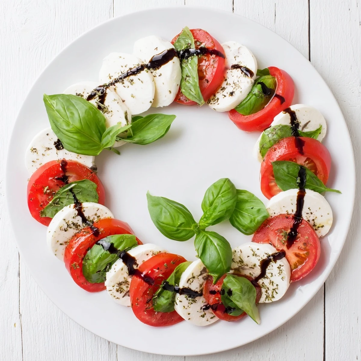 Festive Christmas candy cane Caprese salad arranged with fresh mozzarella slices and ripe red tomatoes on a white serving platter