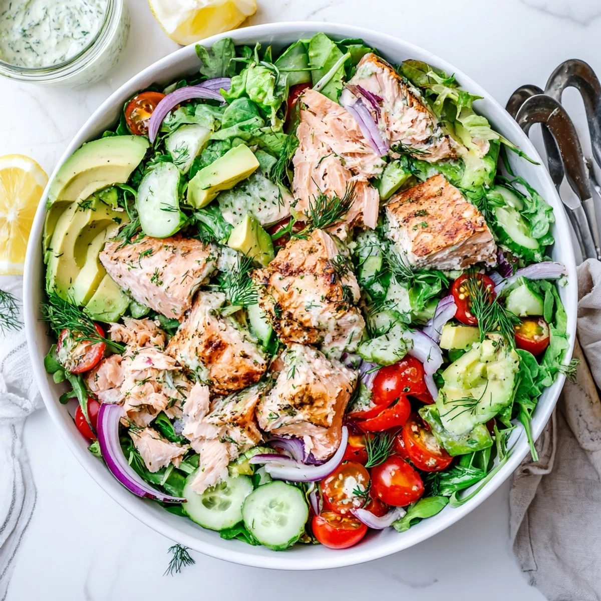 Colorful Ultimate Salmon Salad bowl with flaky baked salmon chunks, fresh mixed greens, cherry tomatoes, avocado, and crisp cucumber drizzled with lemon dill dressing