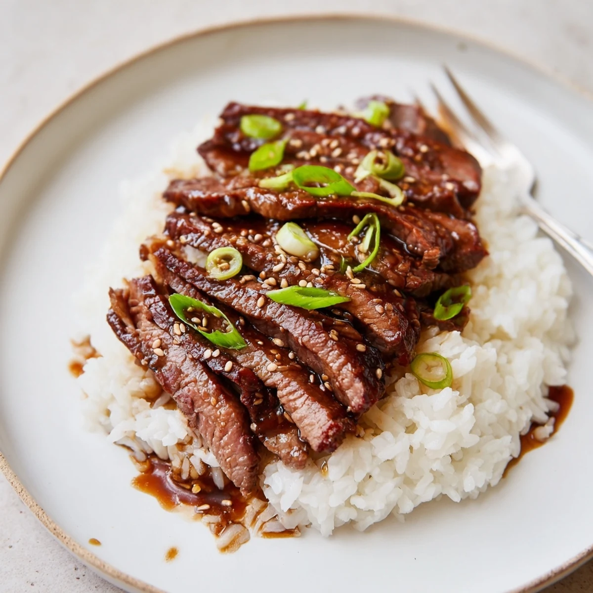 Thinly sliced Korean Beef glistening with sesame and green onions in bowl