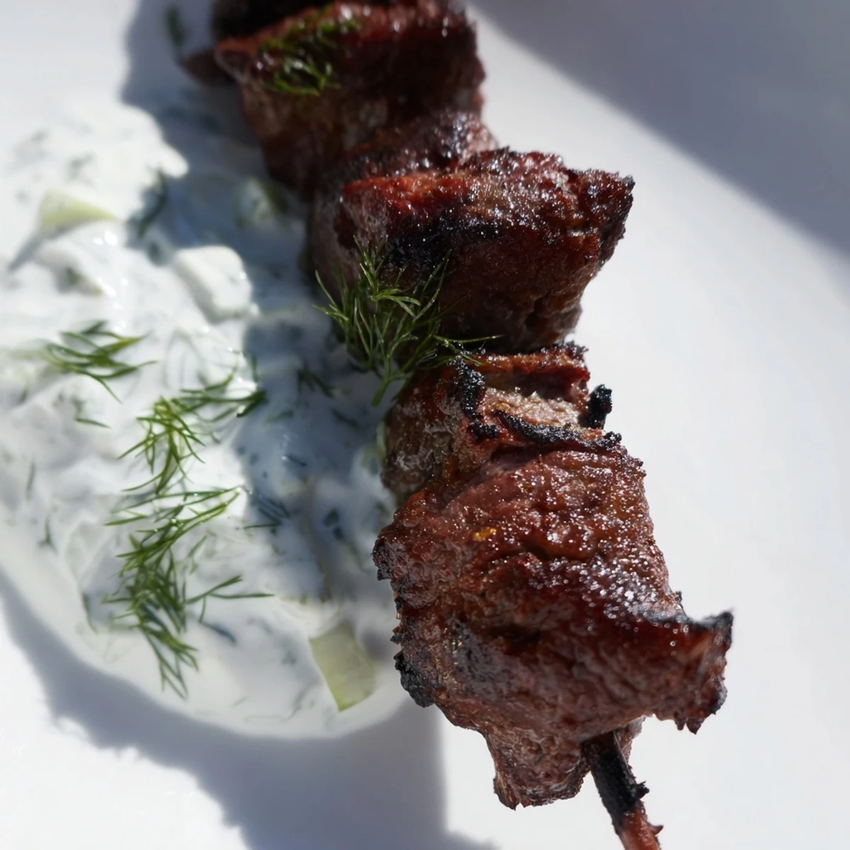 Juicy smashed beef kebabs with crispy golden edges served alongside creamy cucumber yogurt sauce
