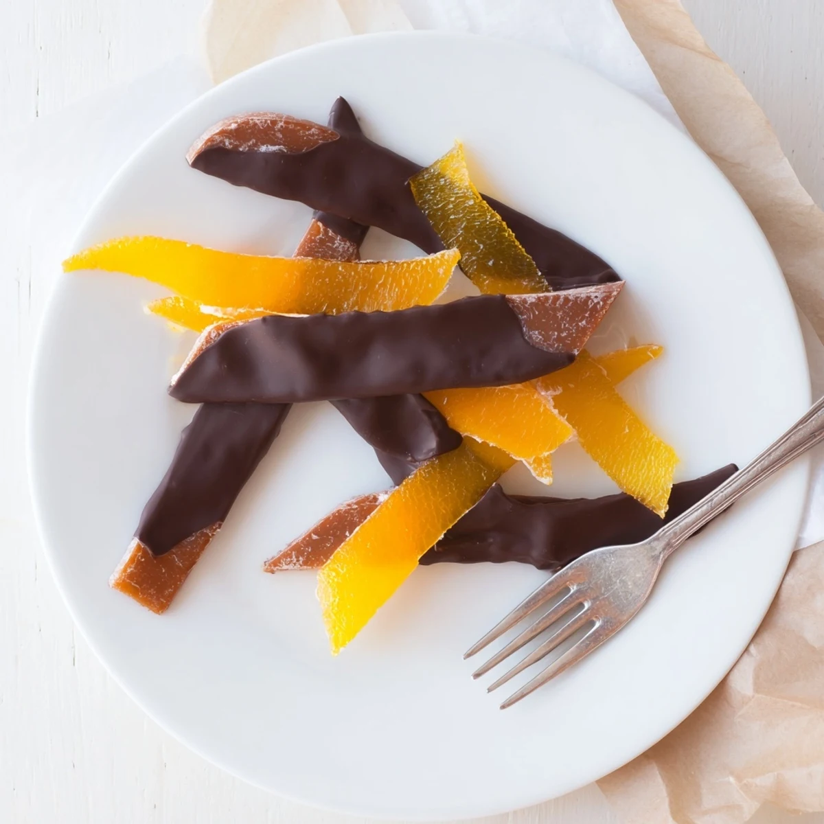 Candied orange strips dipped halfway into velvety chocolate, cooling on a wire rack
