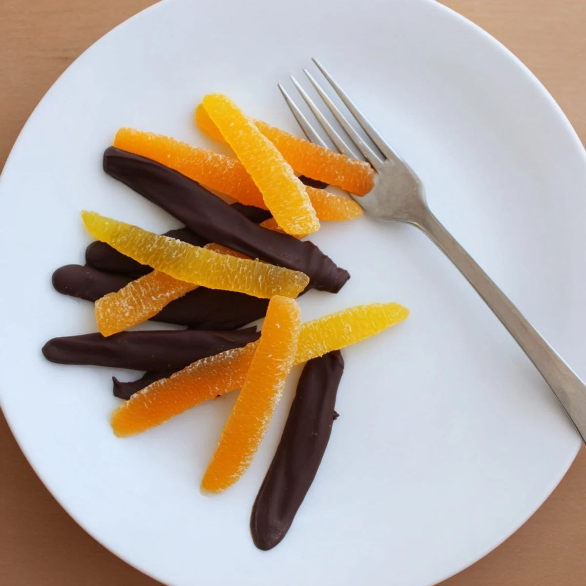 Glossy chocolate covered orange peels arranged on parchment, rich dark coating shining