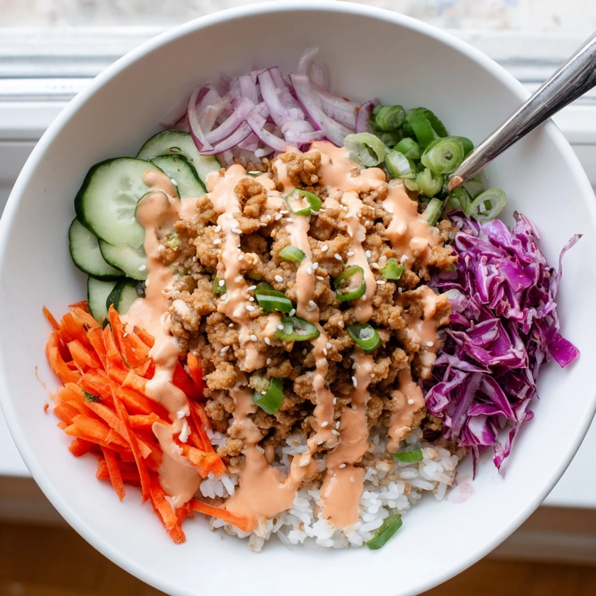 Close-up of spicy Bang Bang Sauce cascading over seasoned Ground Turkey Rice Bowls