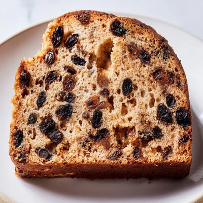 A slice of Irish Tea Cake reveals moist crumb with specks of spice, served with butter on the side.