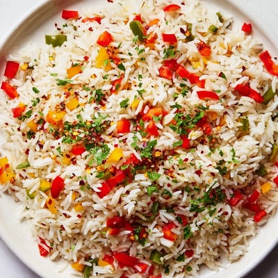 A close-up of colorful Creole Rice Pilaf with Peppers and Onions in a skillet, featuring tender red and green bell peppers. 