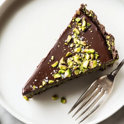 Silky dark chocolate ganache fills a buttery pistachio crust in this elegant tart